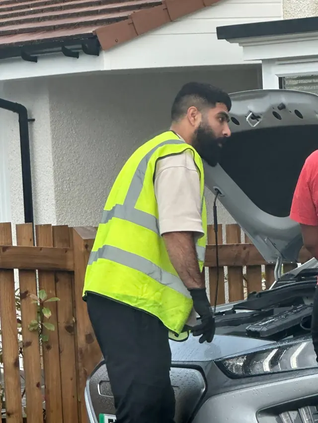 Lifesaver operator assisting beside an open car bonnet
