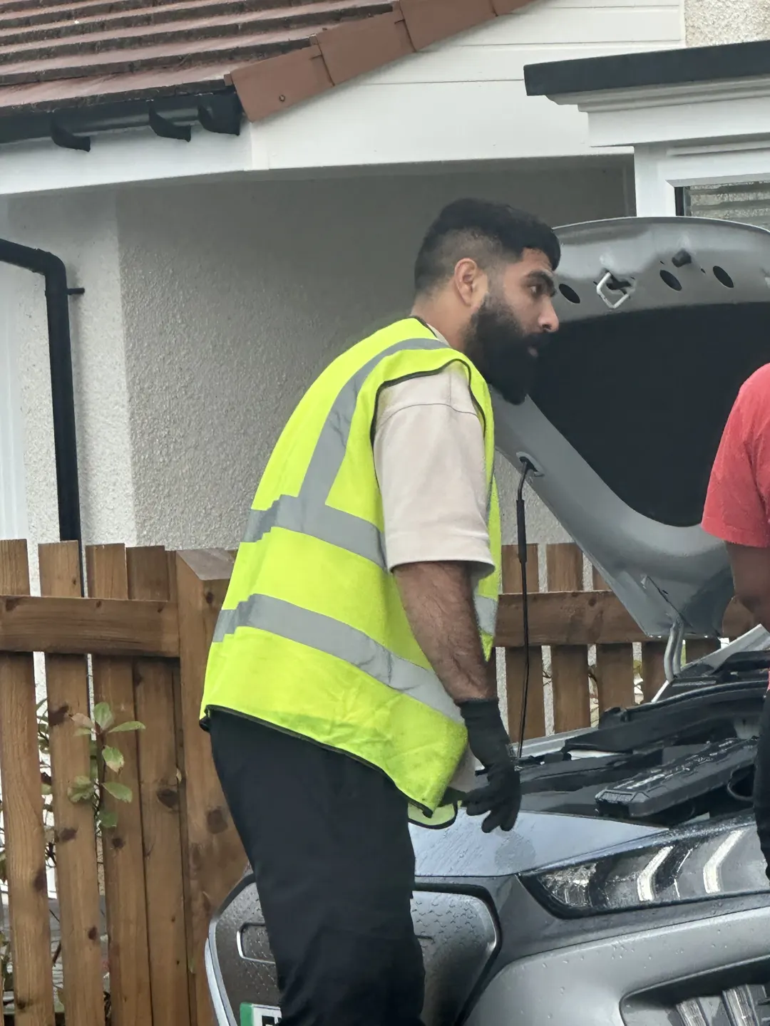 Lifesaver operator beside an open car bonnet during a battery assistance call-out