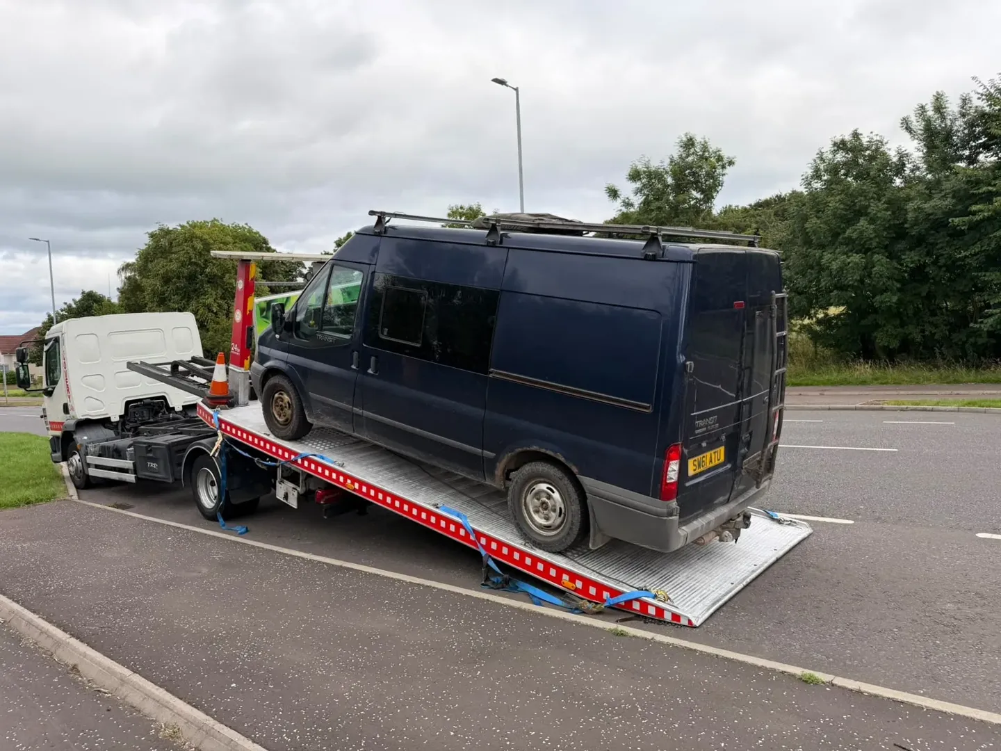 Large black passenger van loaded on Lifesaver tilt-and-slide recovery truck